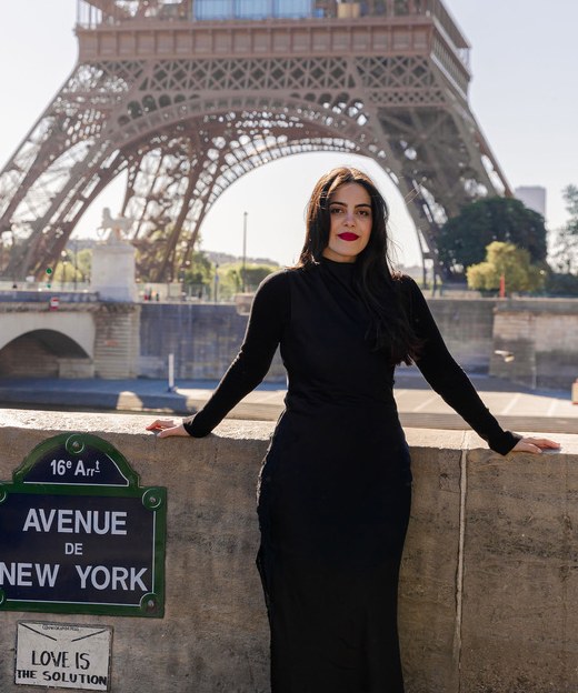 Giovana Kllepper, de vestido preto, apoiada num muro em Paris